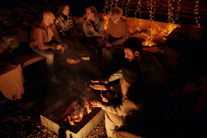 People chilling around fire in backyard