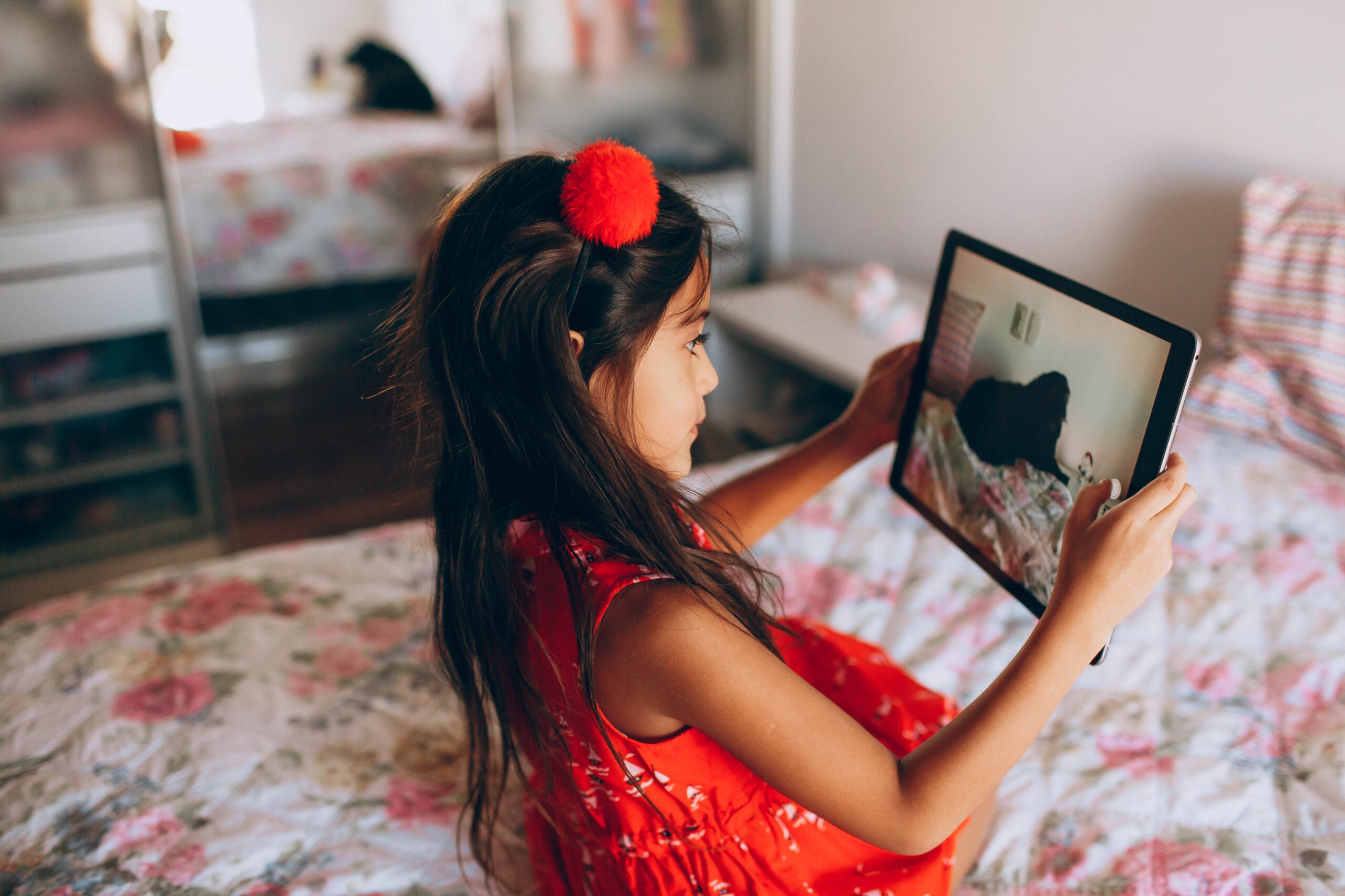 girl in a pink top using a black iPad image