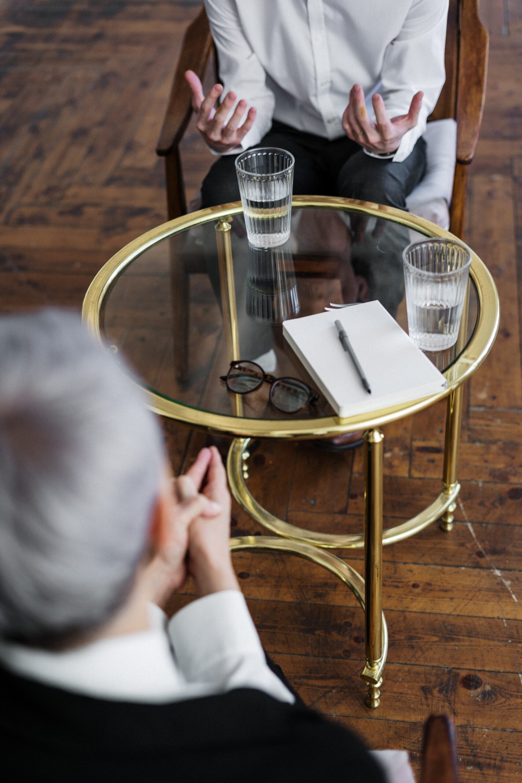 Two people sitting opposite a round glass table