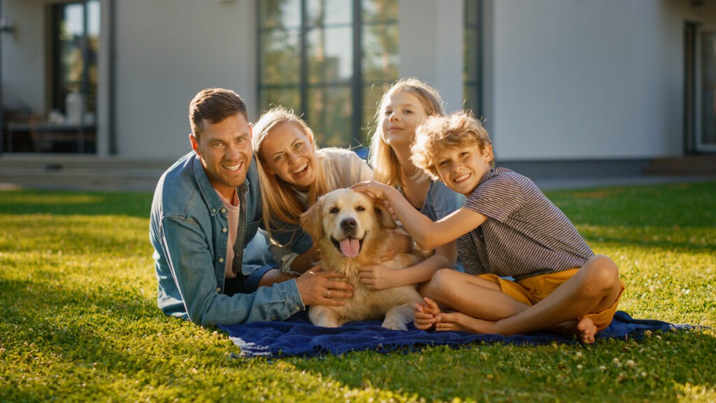 A happy family with their family dog on a backyard lawn