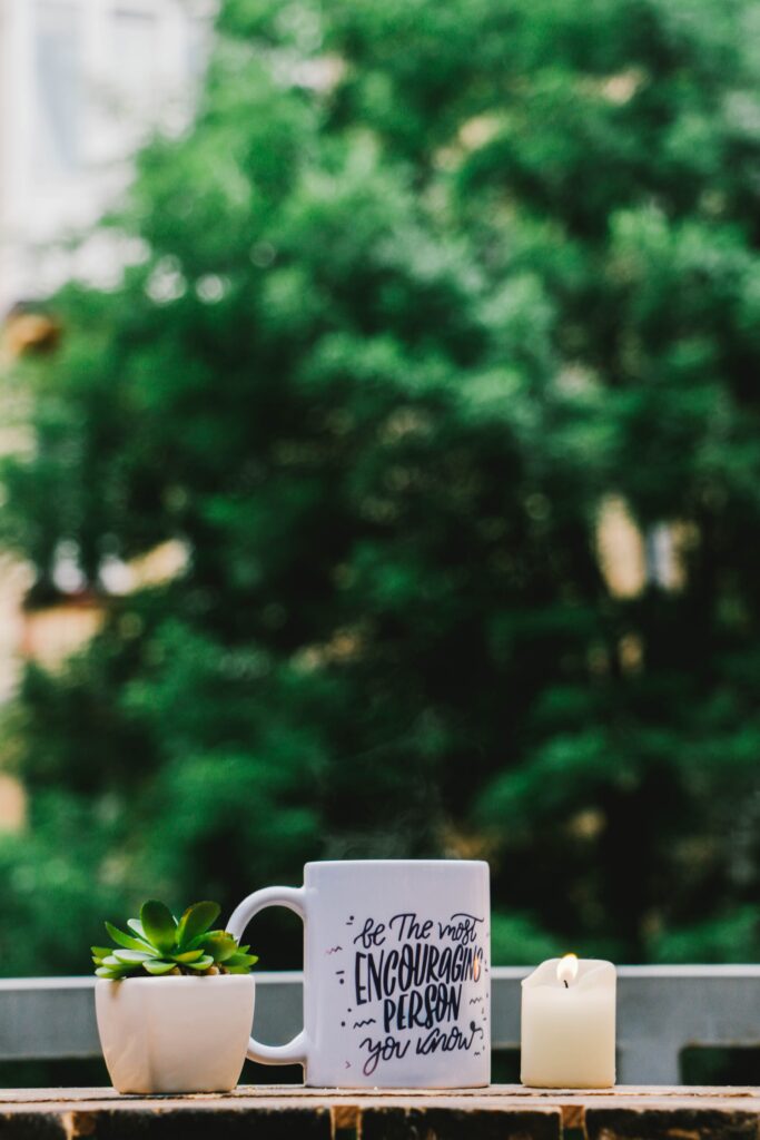 A mug with quotation and succulents and candle image