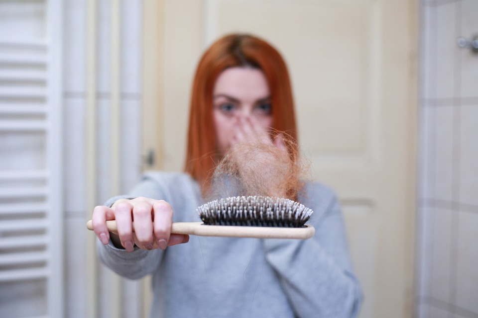 A woman holding a comb with many hair strands image
