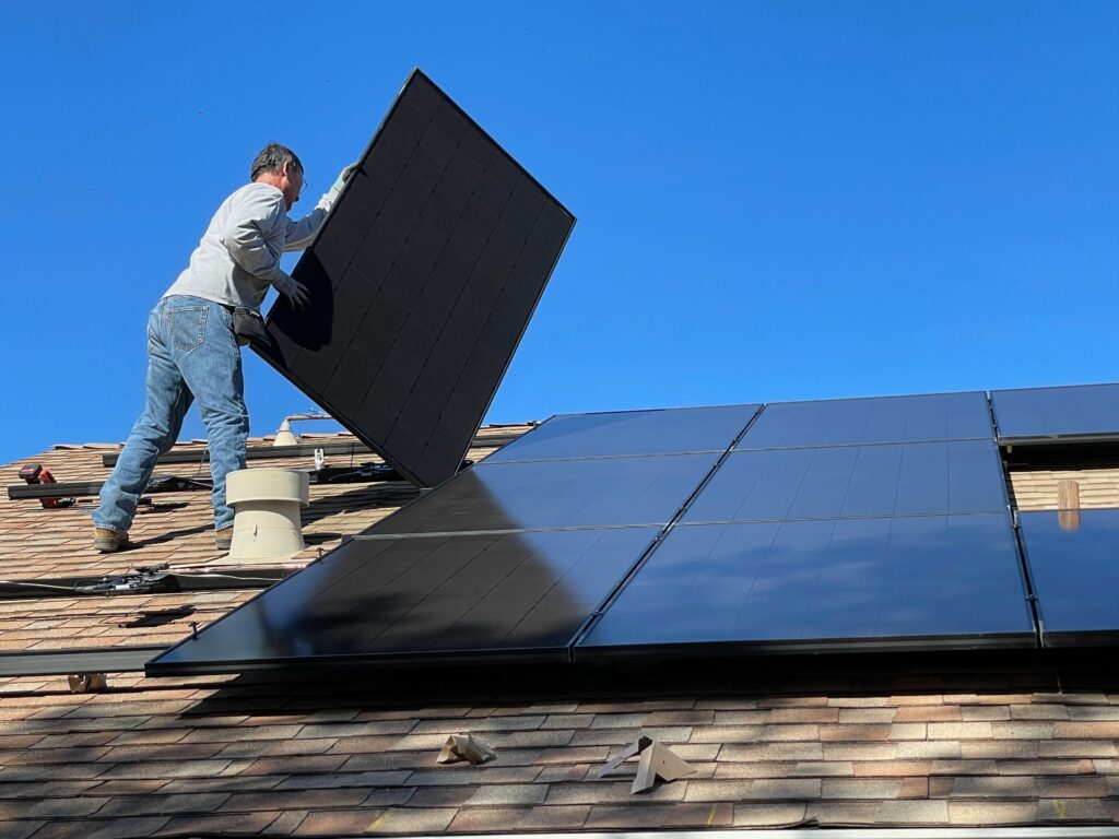  a worker installing solar panels on the roof image