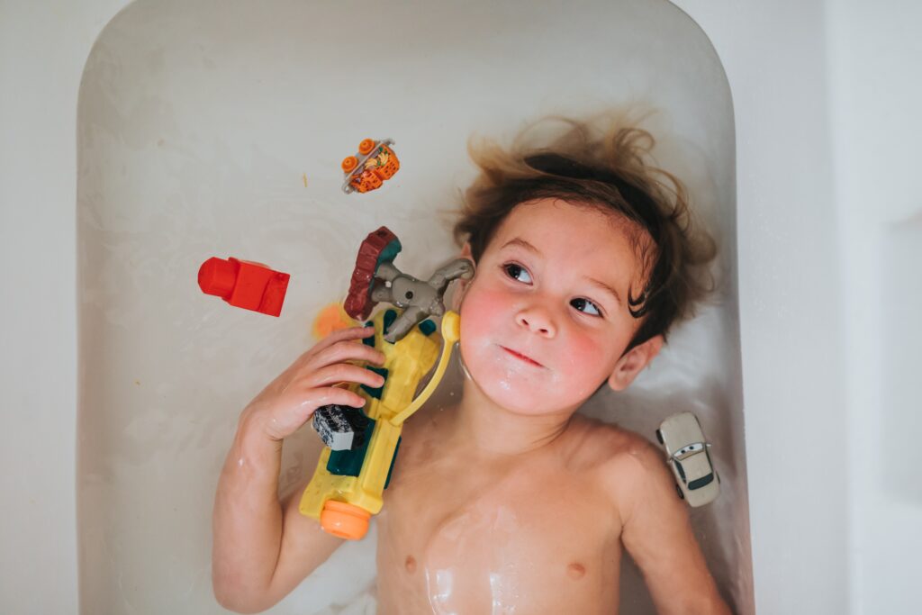a child lying on a tub with toys