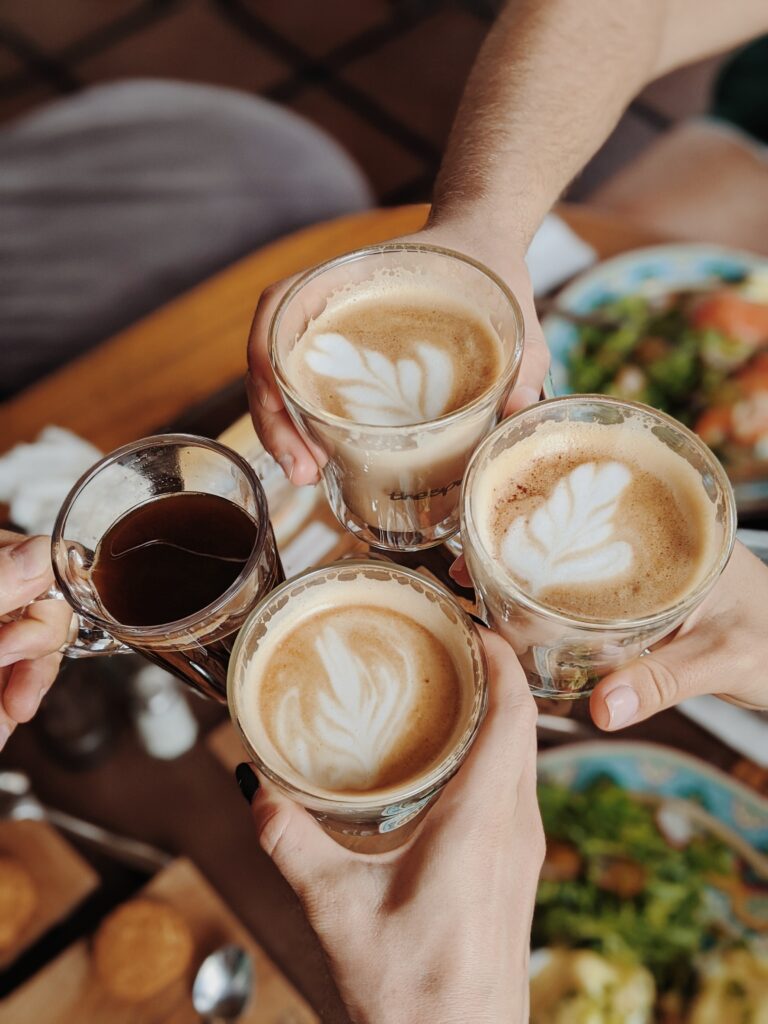 People With Four Drinking Glasses Of Coffee While Making a Toast