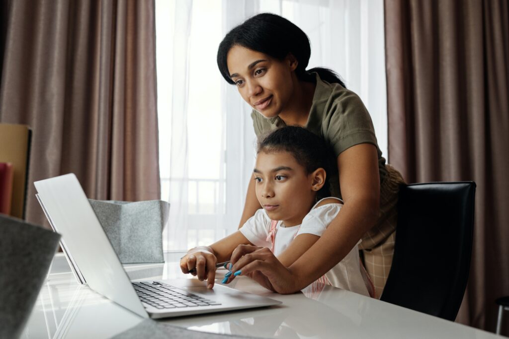 Mother helping her daughter use a laptop image