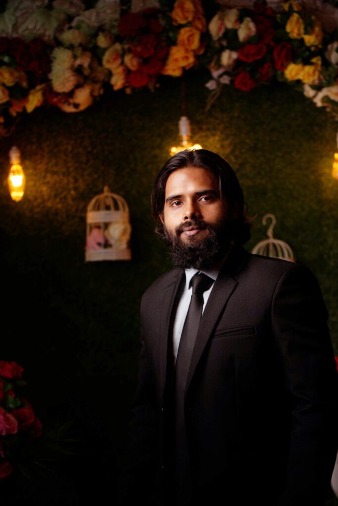 man in black suit under a wedding flower canopy image