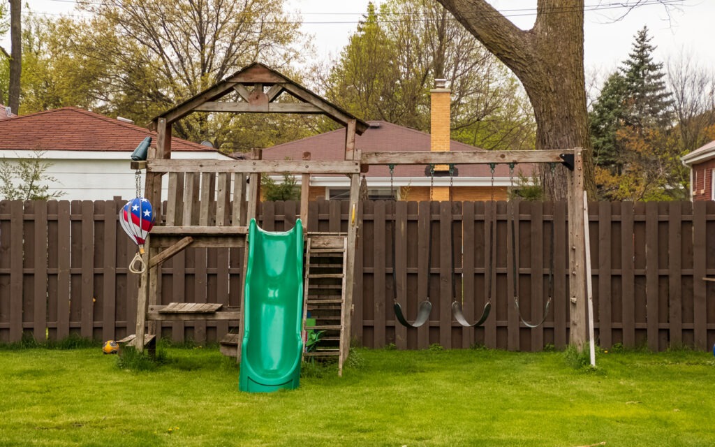 Swing set in backyard during spring season with lush grassy lawn