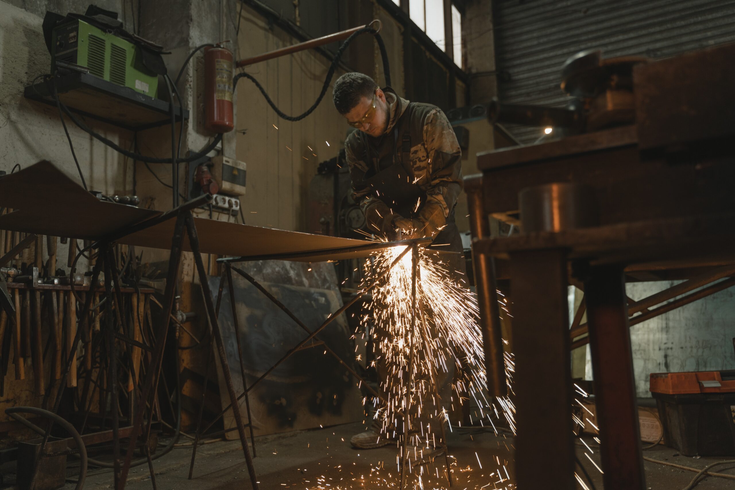 A man in safety glasses welding a metal bar