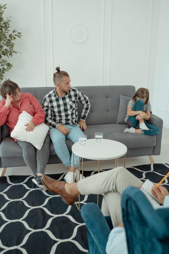 A couple sitting on a couch with their daughter at a therapy session