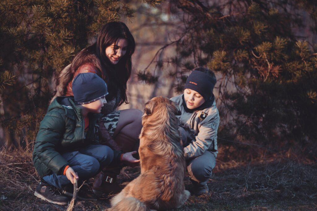 female and children crouch beside a dog image