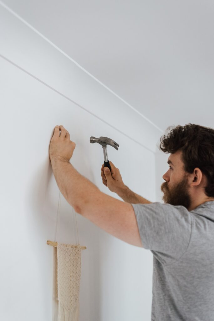 man hammering nail into wall during housework image