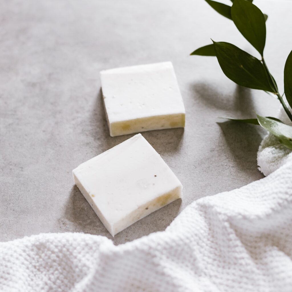  two white soap bars, with a white blanket and plant on the floor tile image