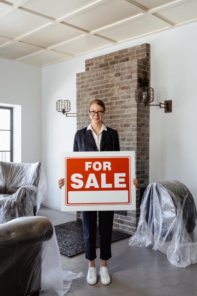 A woman holding a sign that says for sale in an apartment image