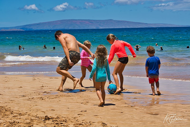 Family playing soccer on the beach