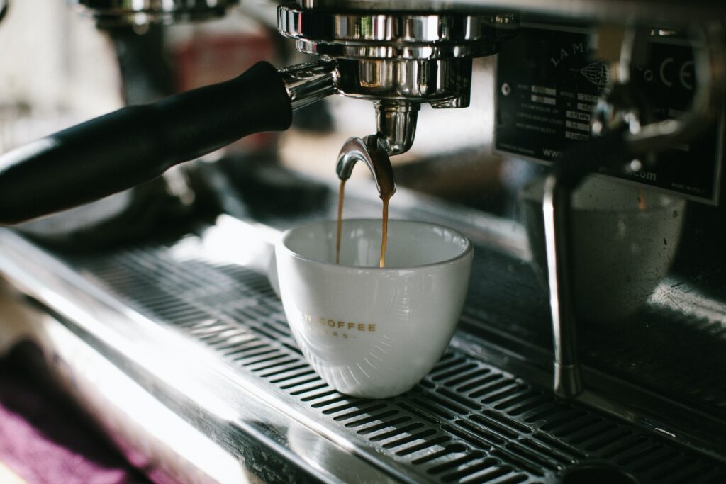 an image of stainless steel coffee machine pouring hot brewed coffee in a mug