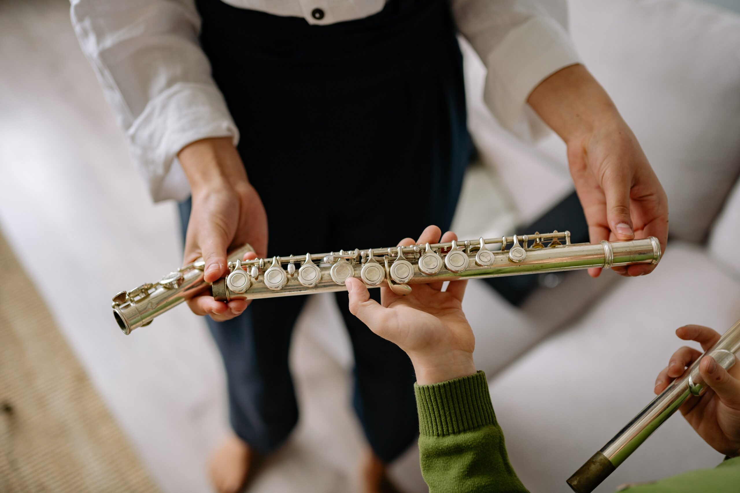 A person handing a flute to a child
