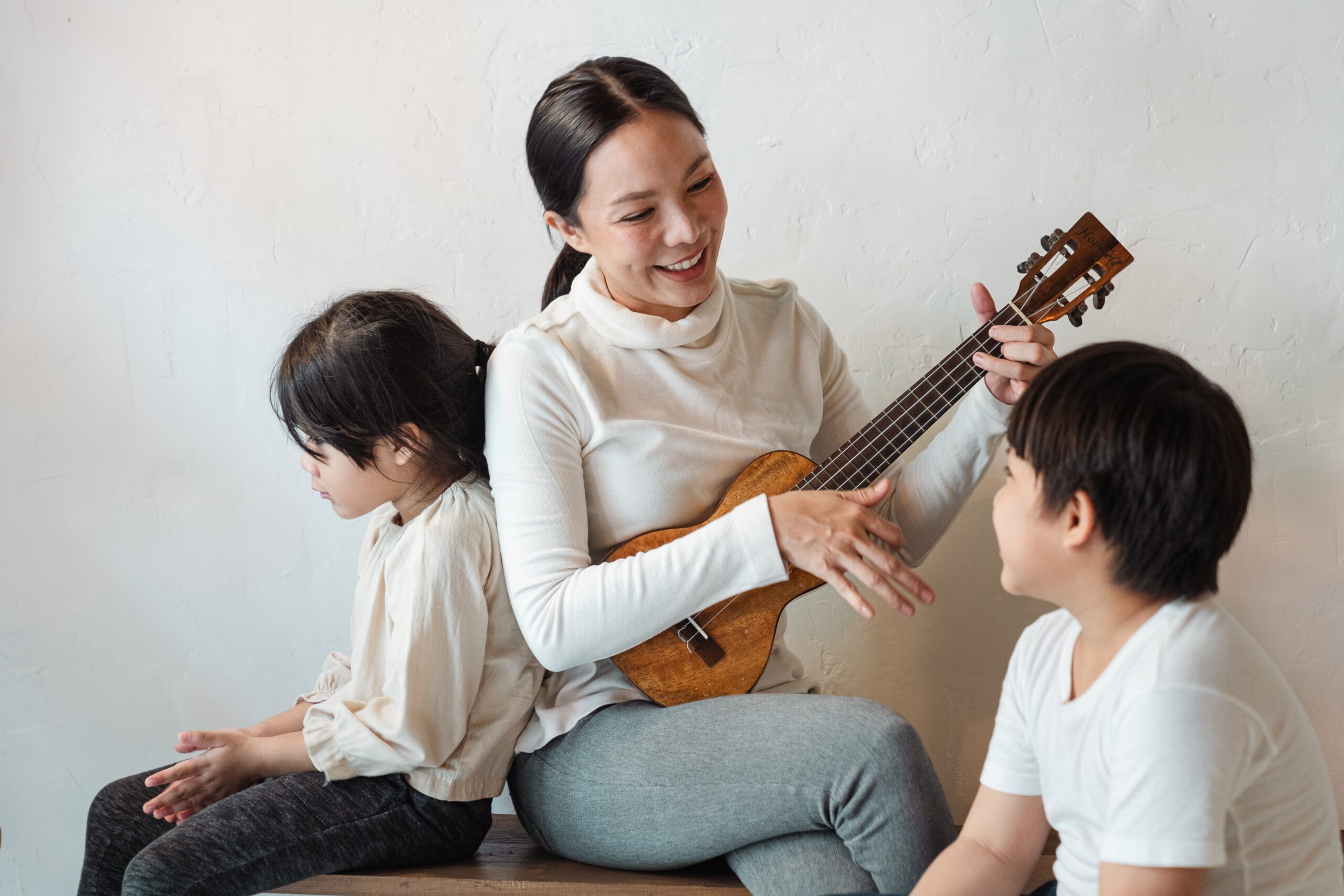 A woman playing a ukulele for her children