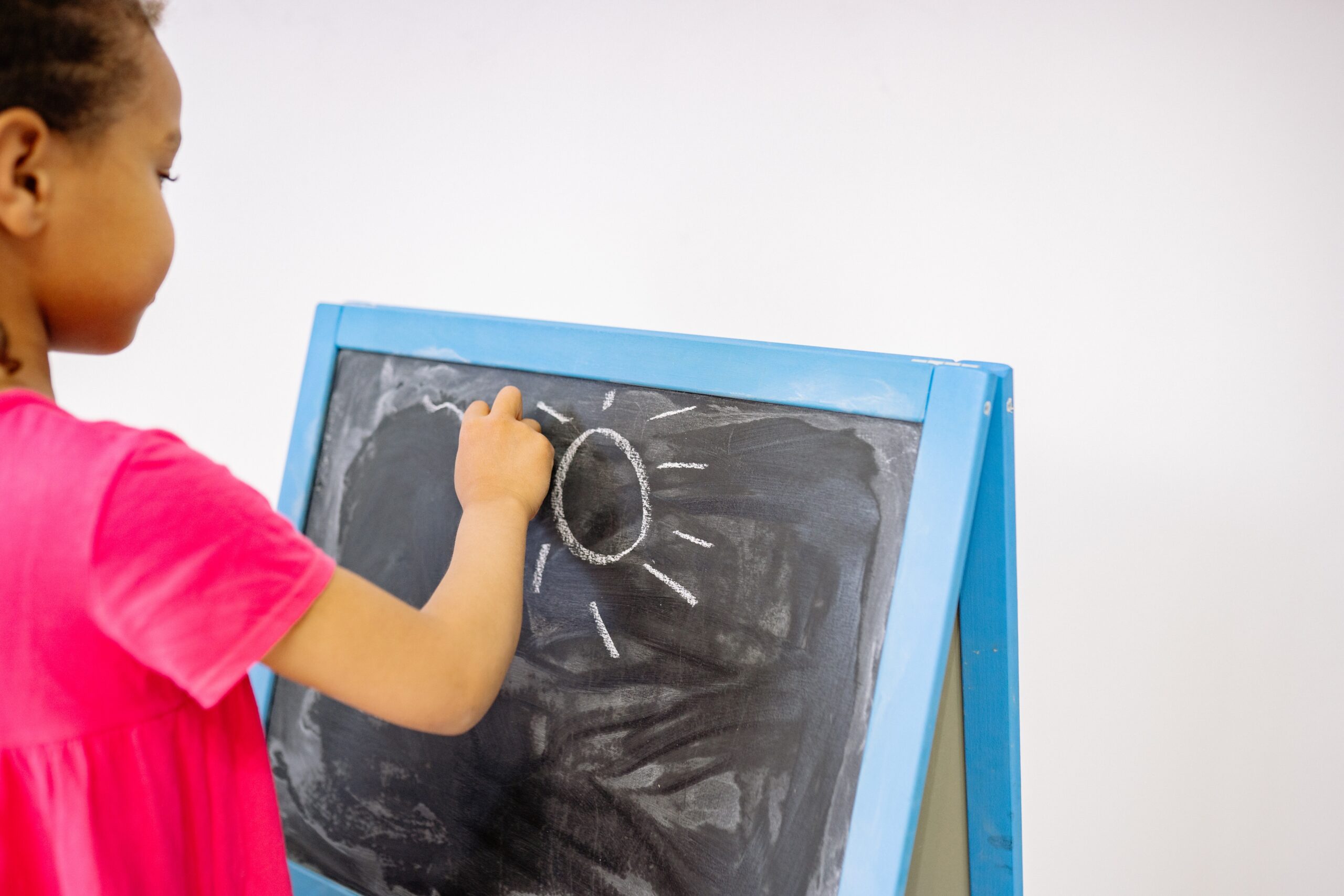 Girl in pink dress drawing on a blackboard image