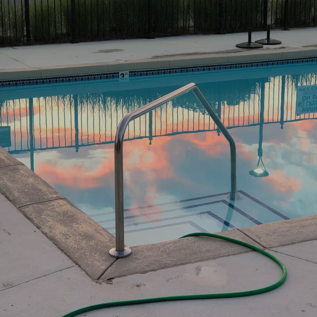 Pool with railing near hose and fence in hotel yard image