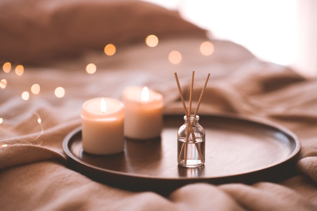 Scented candles and bamboo sticks in a bottle on a tray