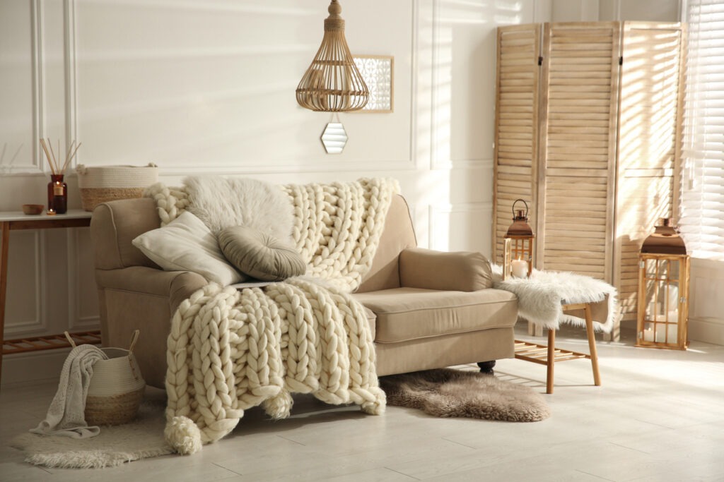 A cozy living room with a large, knitted throw and comfy cushions