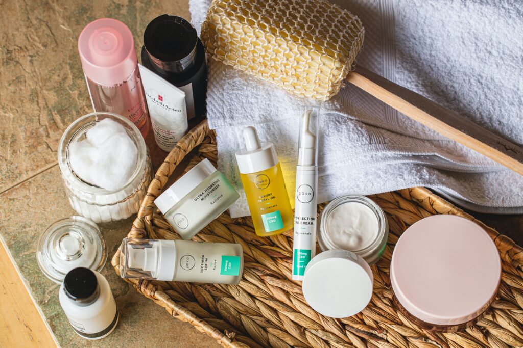 a variety of creams and serums placed on a native basket with white towel