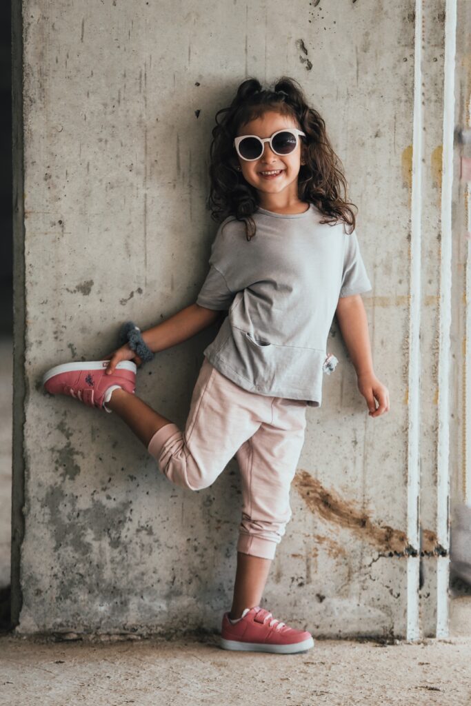 girl in gray shirt smiling while wearing sunglasses image
