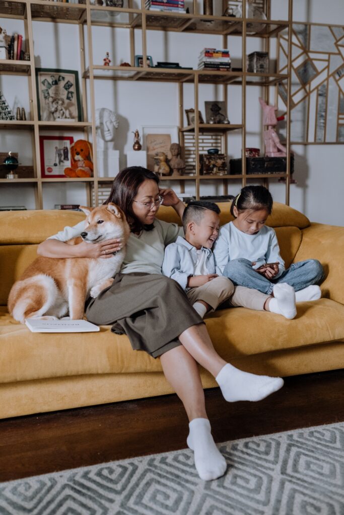 A Mother Sitting on the Couch with Her Kids and Their Dog image
