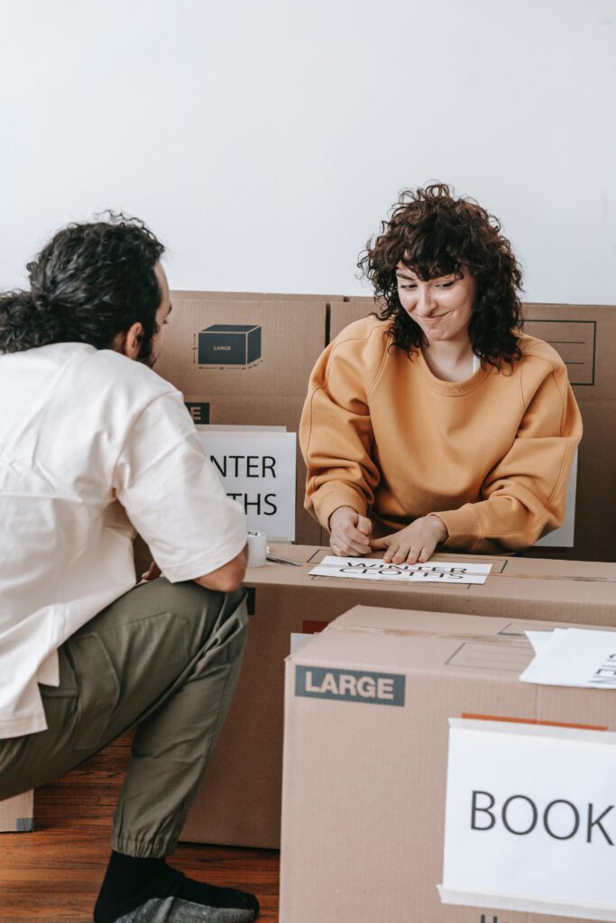 A couple packing things in boxes image