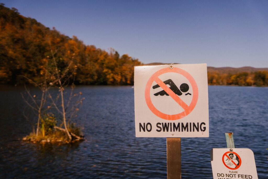 No swimming sign in front of a lake image