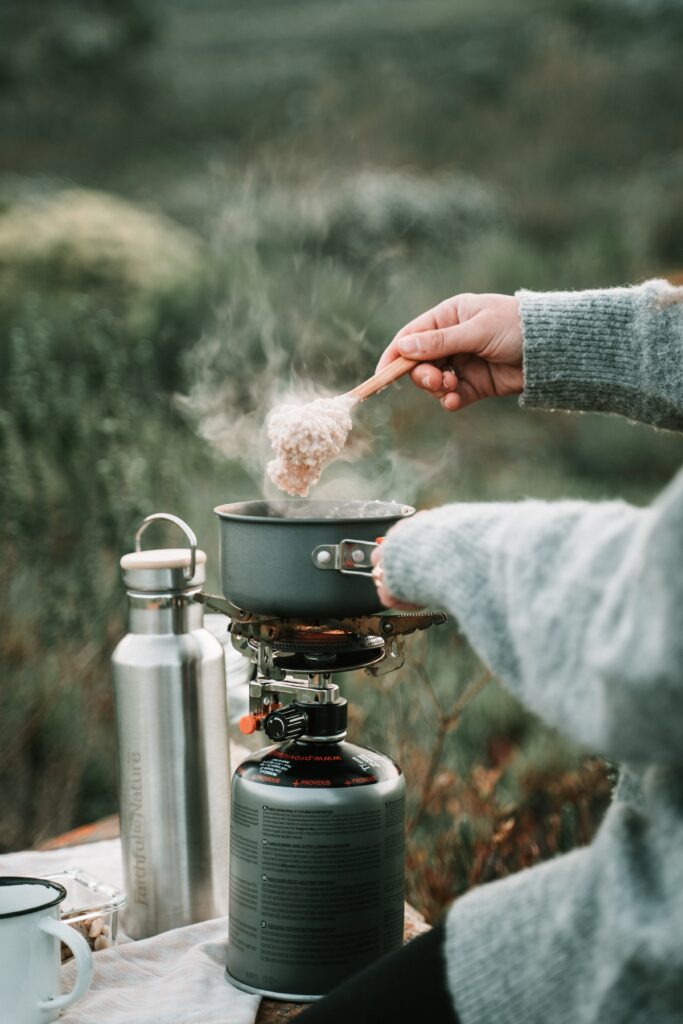 A person cooking oatmeal over a portable stove while camping image
