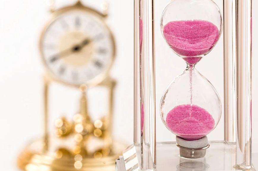 an hourglass containing pink molecules