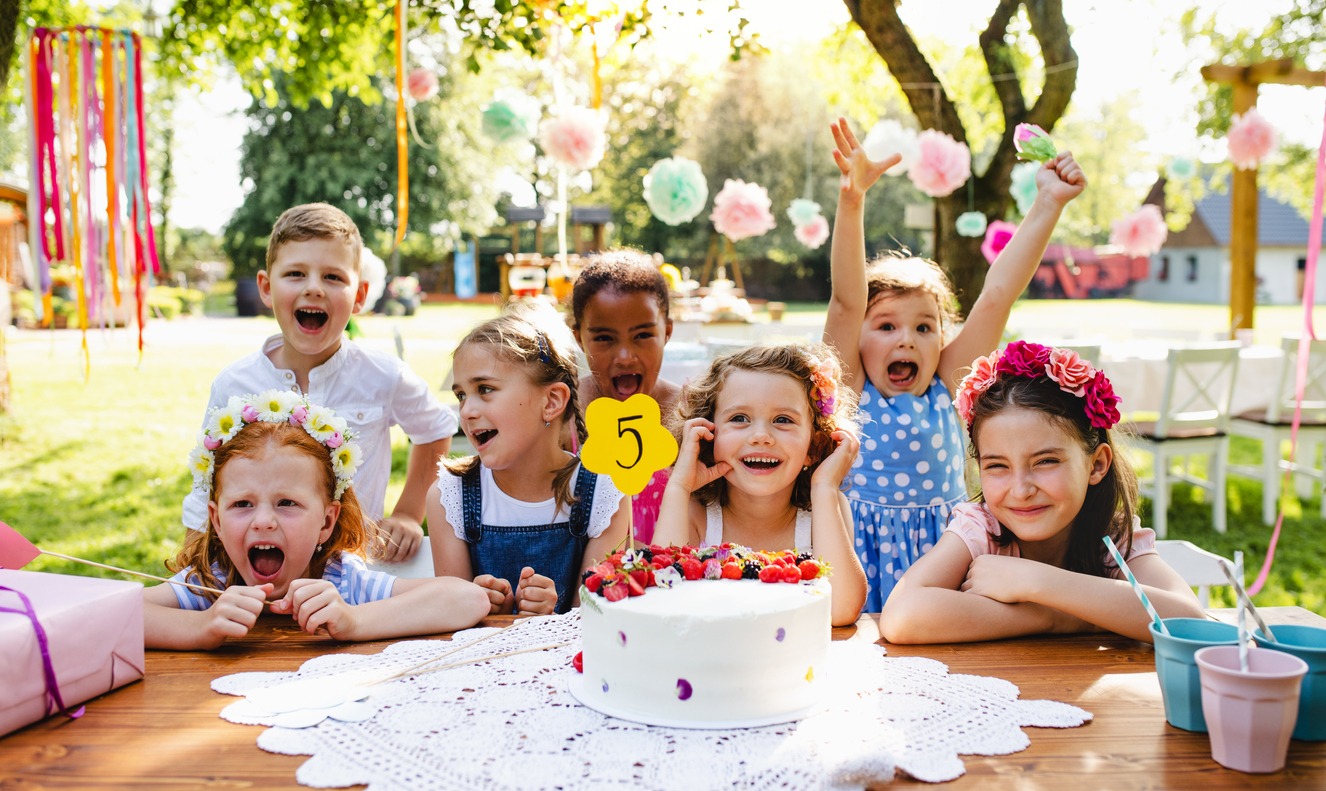 a group of children around a table on a birthday party in a garden