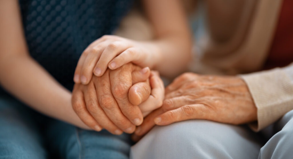 An old and young person holding hands