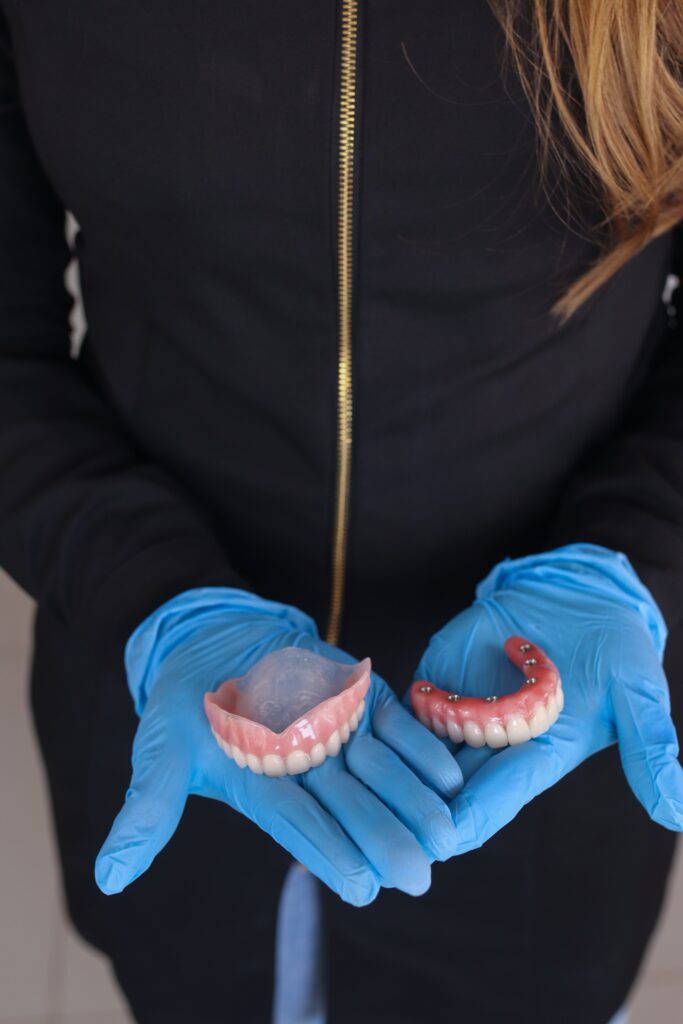A person wearing blue gloves holding dentures image