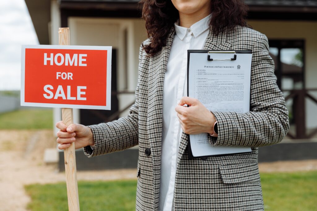 A woman holding a “home for sale” sign image