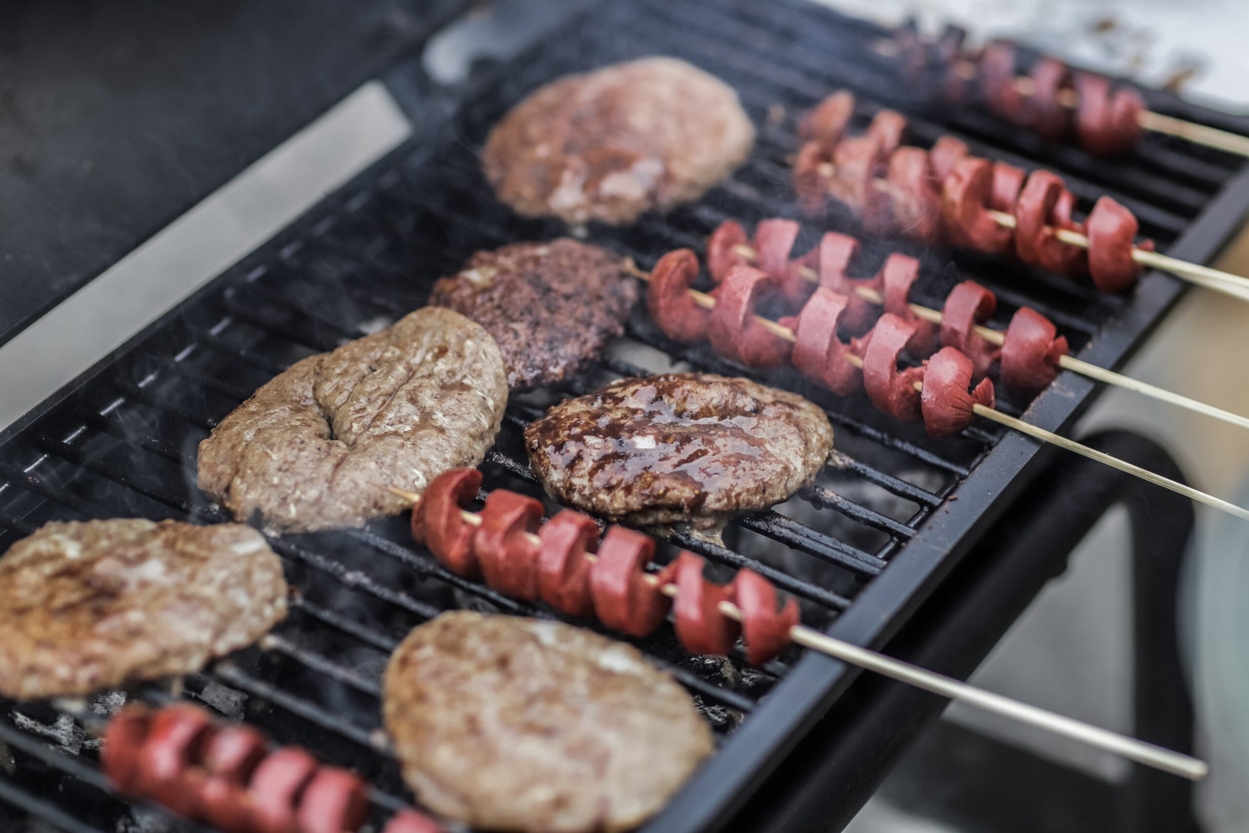 Steaks and skewered sausages on a grill image