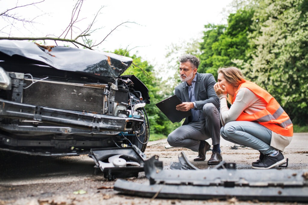 Two people looking at the car on the road after an accident