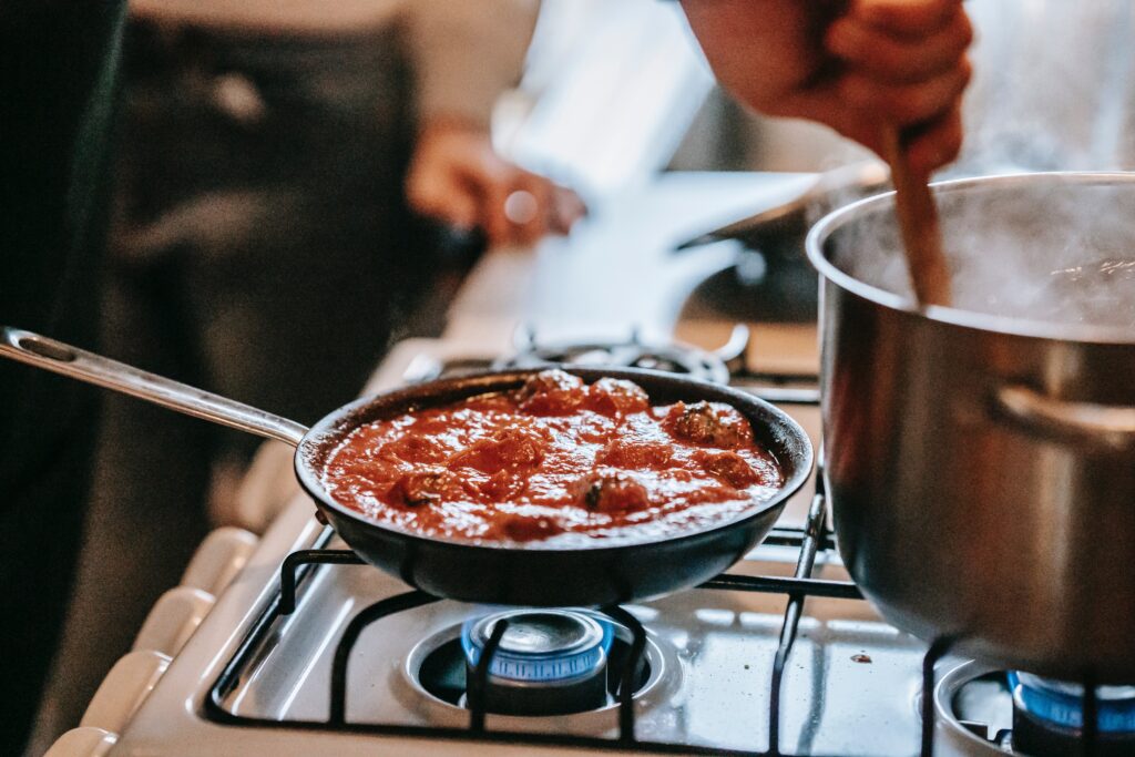 faceless person preparing meatballs with tomato sauce in the kitchen image