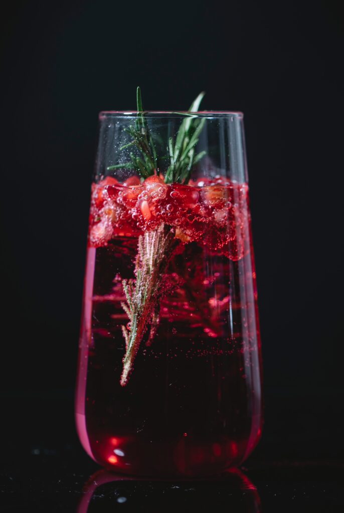 Glass of fresh cocktail with pomegranate and rosemary