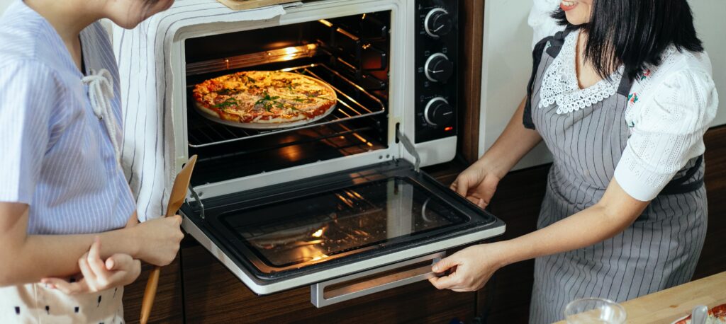 women putting pizza in oven image