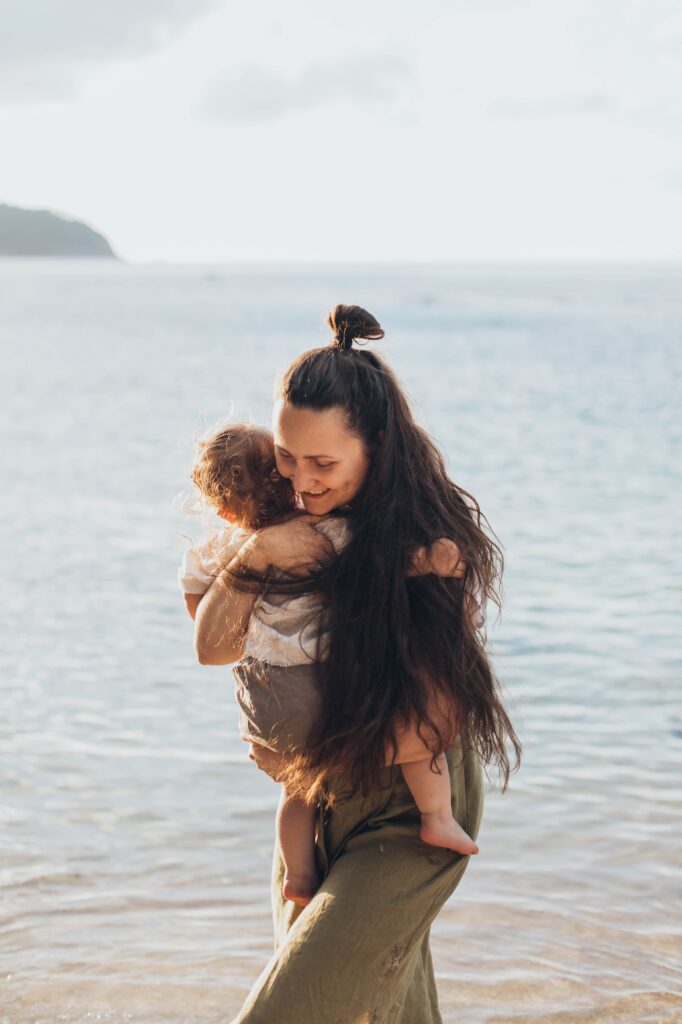 A woman carrying her child along the beach. image