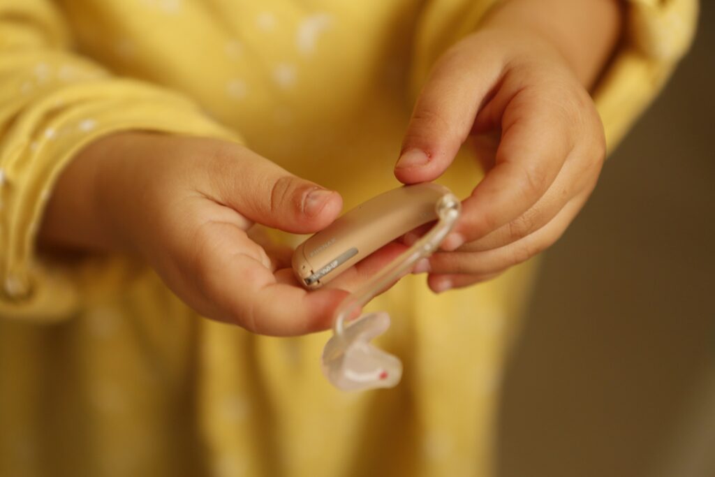 A child holding a hearing aid device