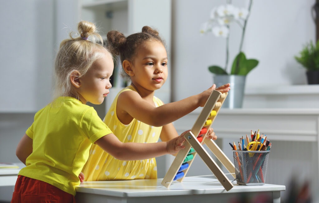 children-of-different-races-sit-together-at-the-table-and-count-on-the-abacus image