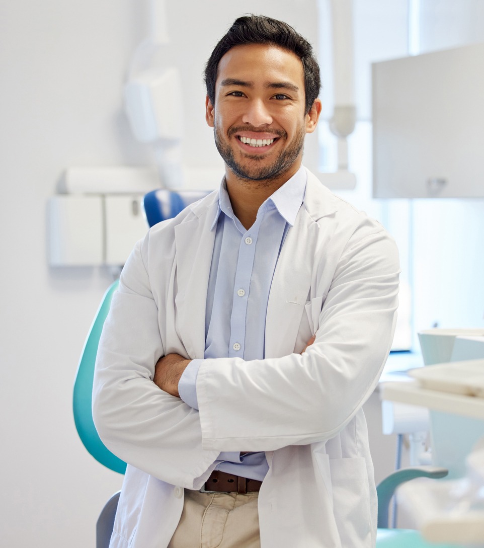 A young dentist smiling in his office