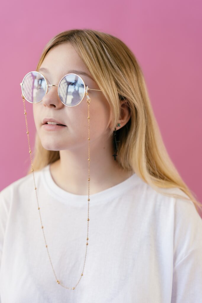  Young girl in white crew neck shirt wearing gold framed eyeglasses
