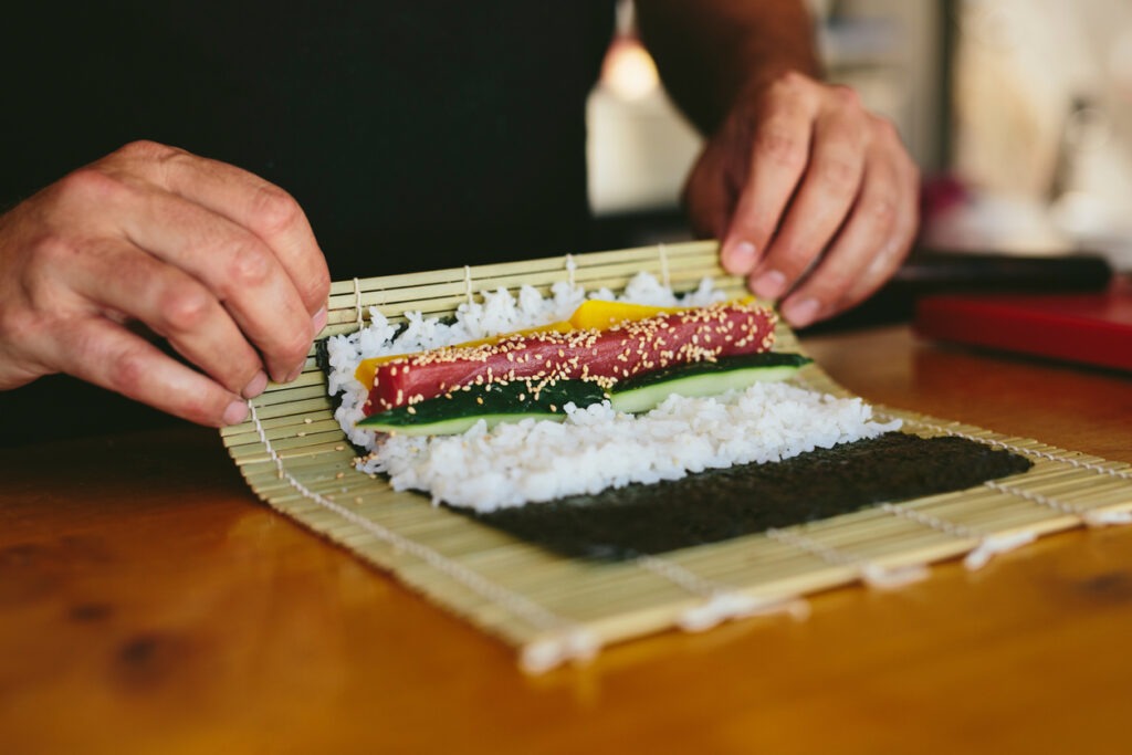 Faceless view of chef rolling sushi with makisu working in food truck on street