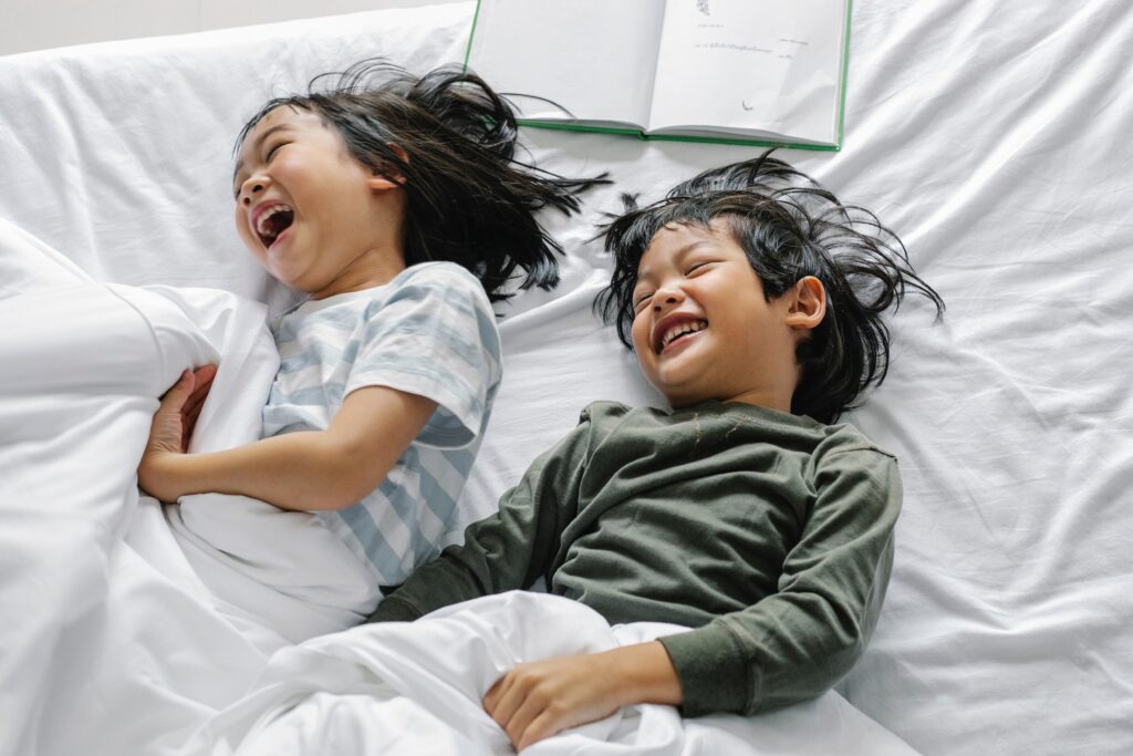 Cheerful Asian Kids having fun in bed