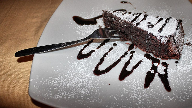 Torta caprese with confectioner's sugar and chocolate sauce image